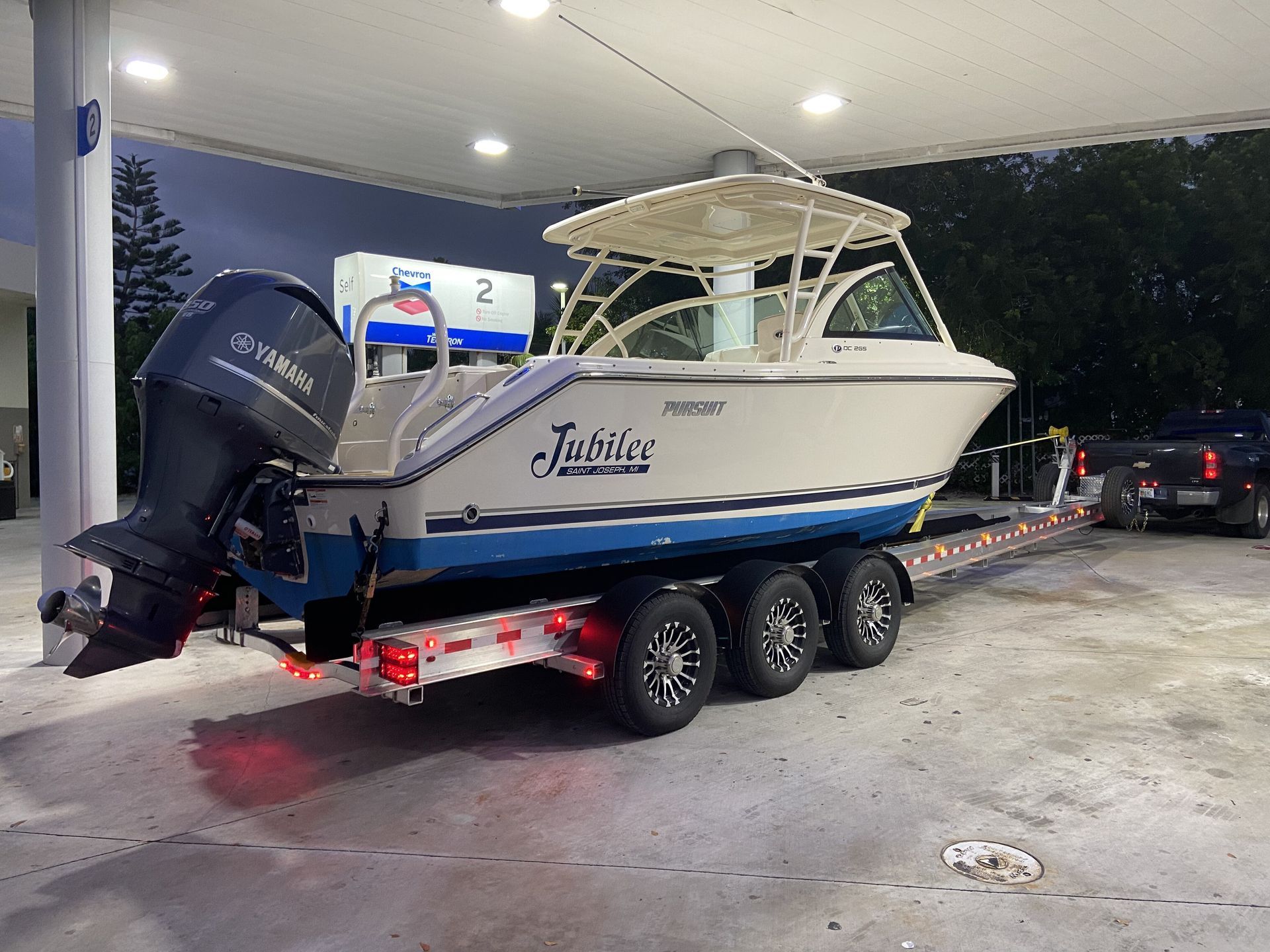 A boat is on a trailer at a gas station.