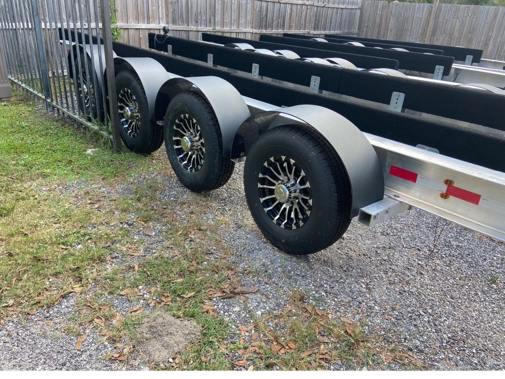 A boat trailer is parked in front of a fence.