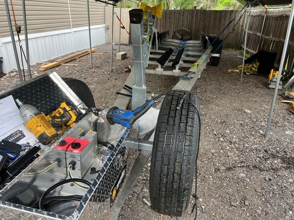 A boat trailer is being built in a gravel lot.