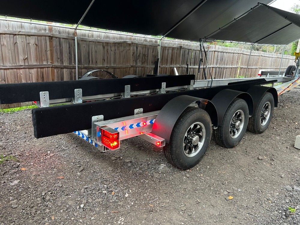 A boat trailer is parked in front of a wooden fence.