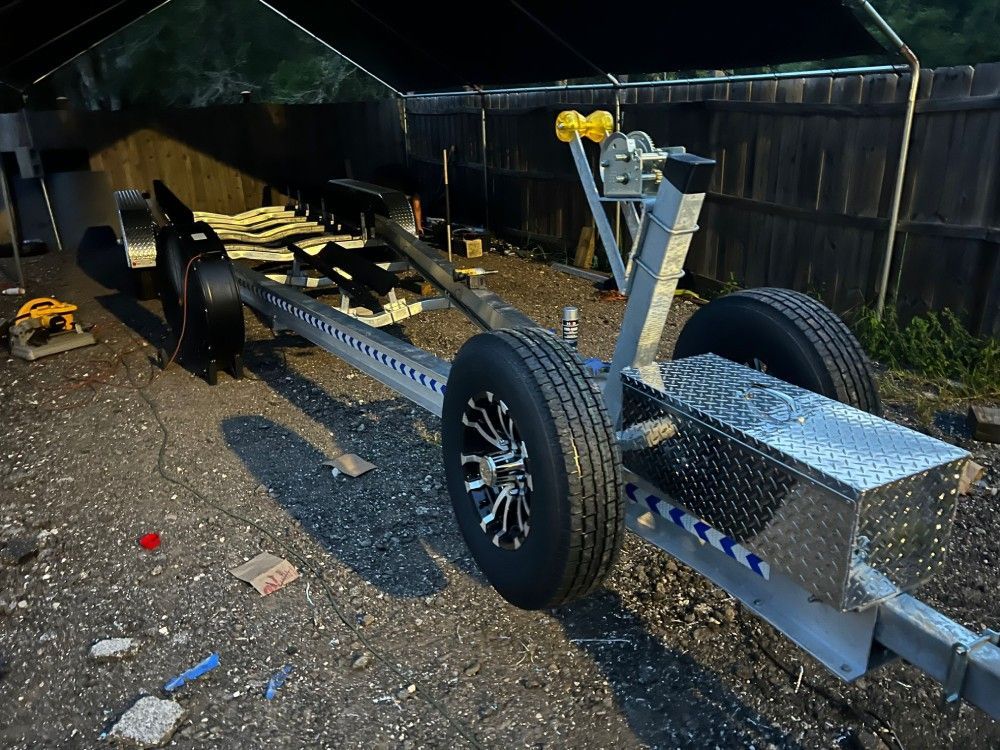 A boat trailer is sitting on the ground under a tent.