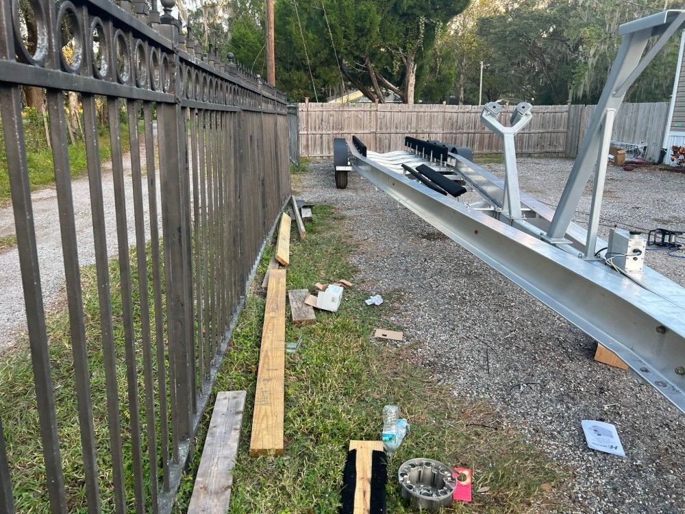 A metal fence is surrounded by a lot of junk in a yard.