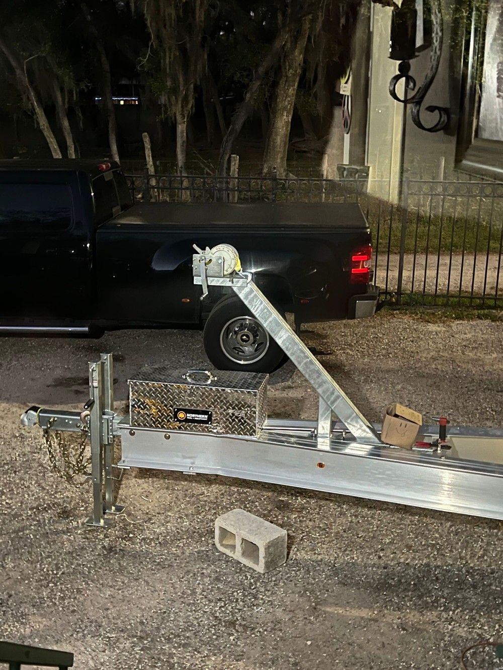A black truck is parked next to a boat trailer.