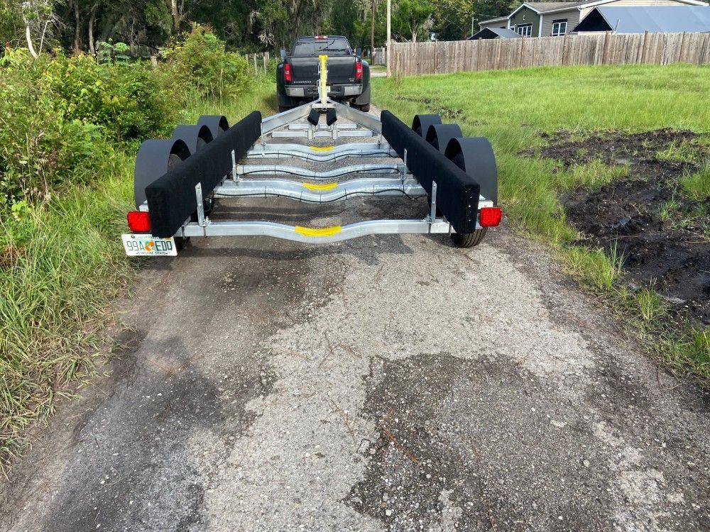 A truck is driving down a dirt road next to a boat trailer.