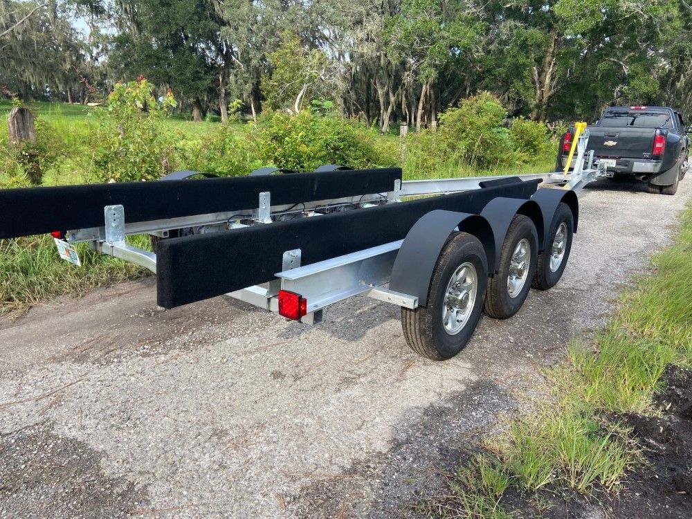 A boat trailer is parked on the side of a dirt road.