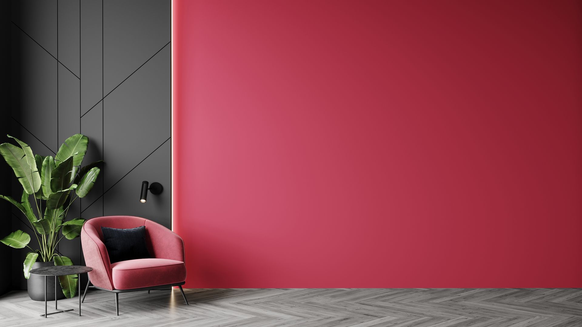 A pink velvet armchair and a leafy green plant sit in a room with a red feature wall and a geometric dark gray panel.