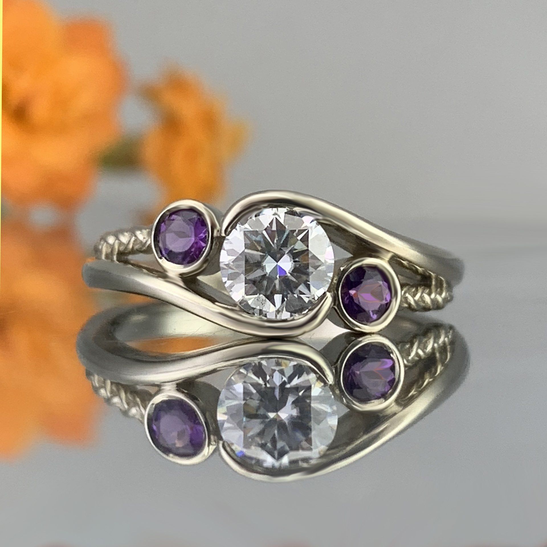 A ring with a diamond and purple stones is sitting on a table.