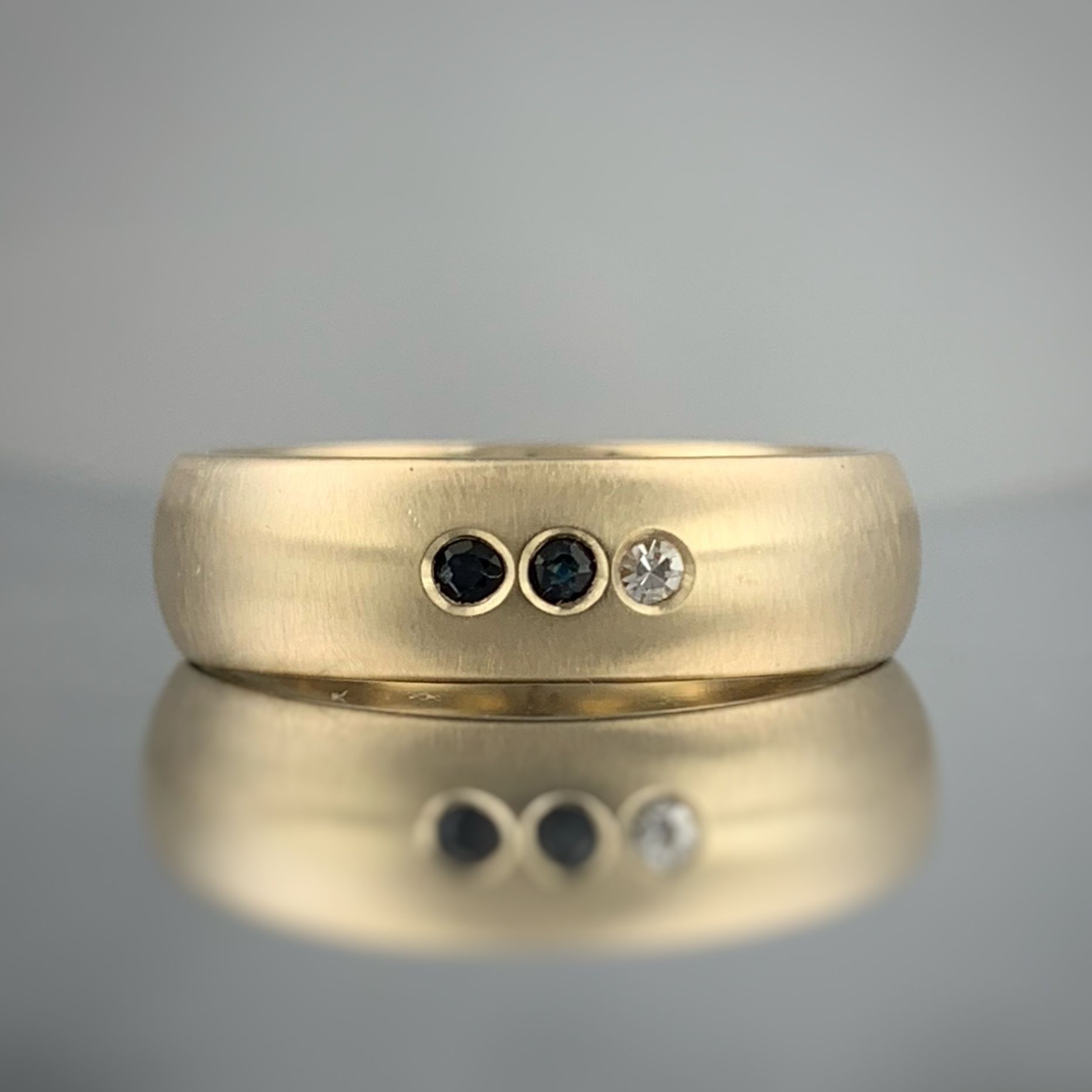 A close up of a gold ring with three diamonds on a table.