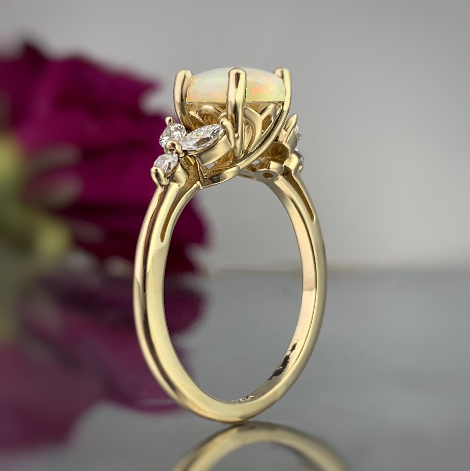 A yellow gold ring with a purple flower in the background