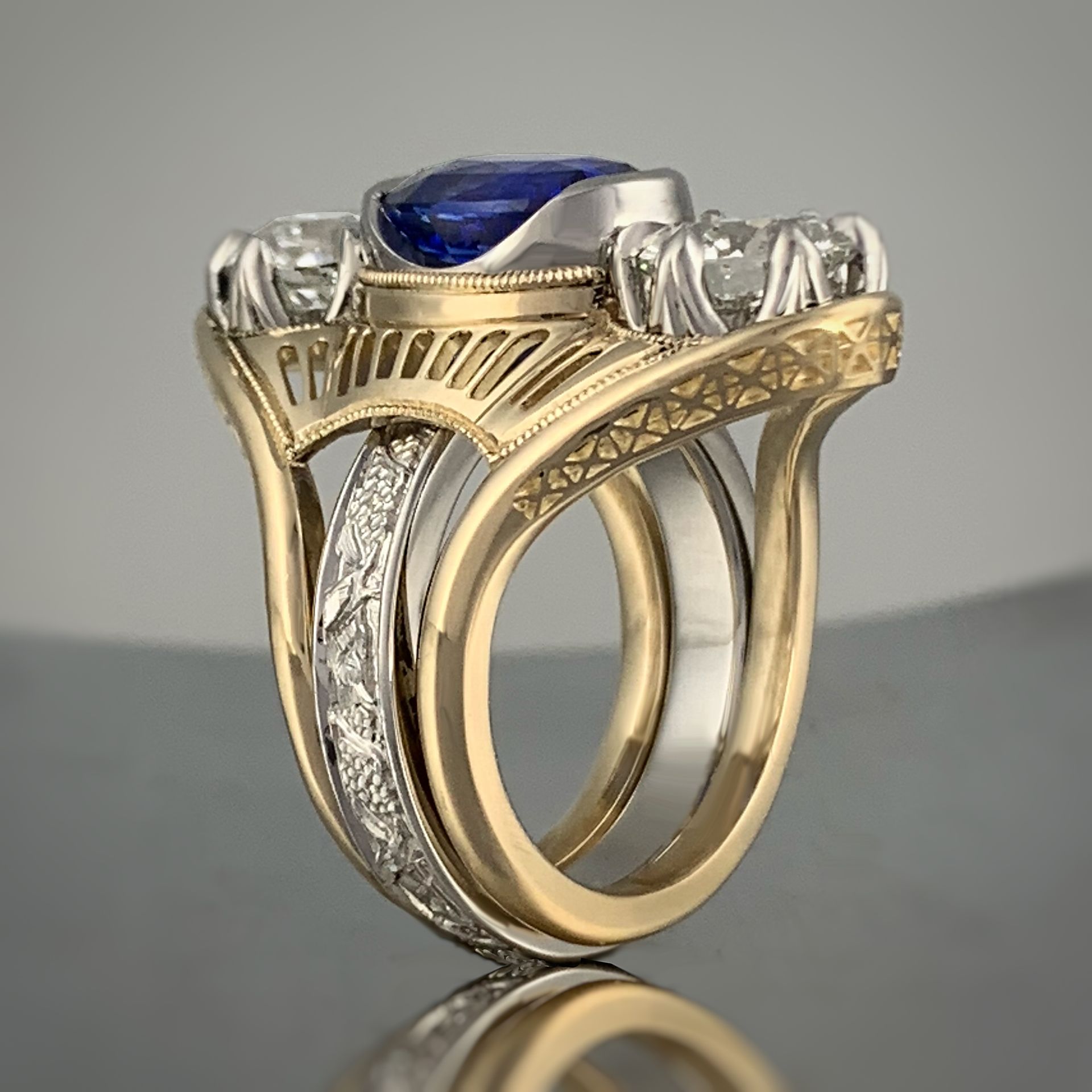 A diamond and sapphire ring with a purple flower in the background