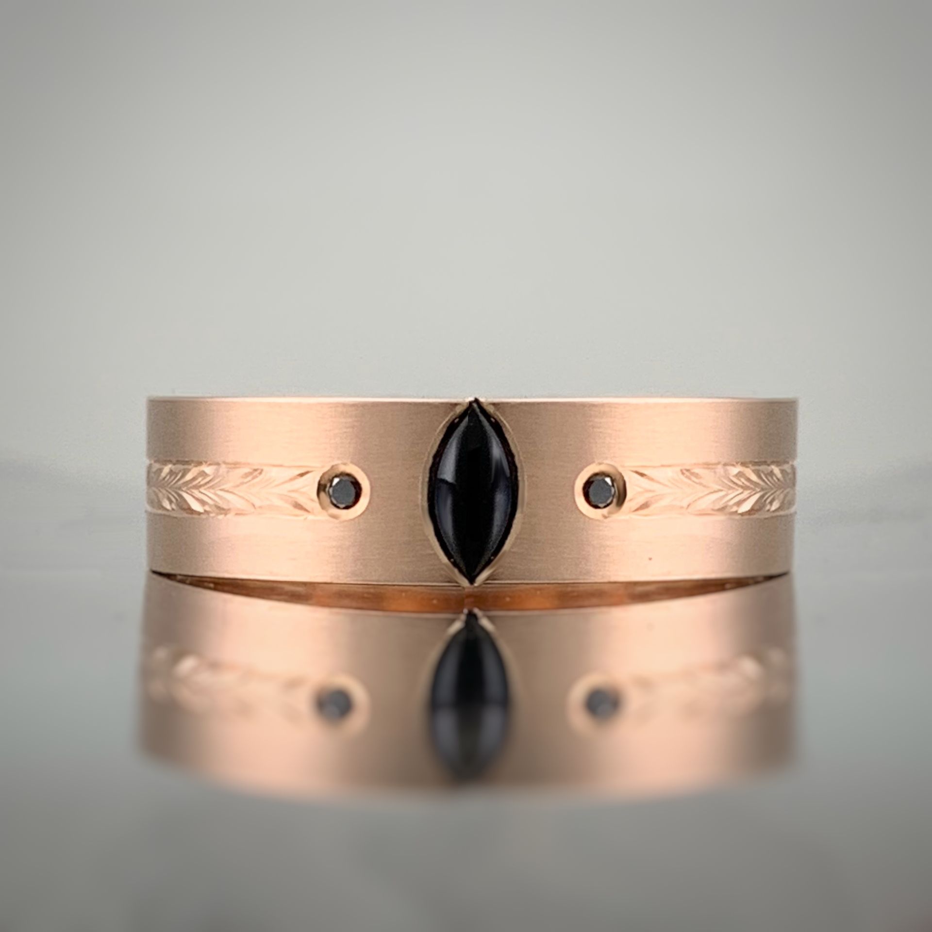 A gold ring with a black stone in the middle is sitting on a table.