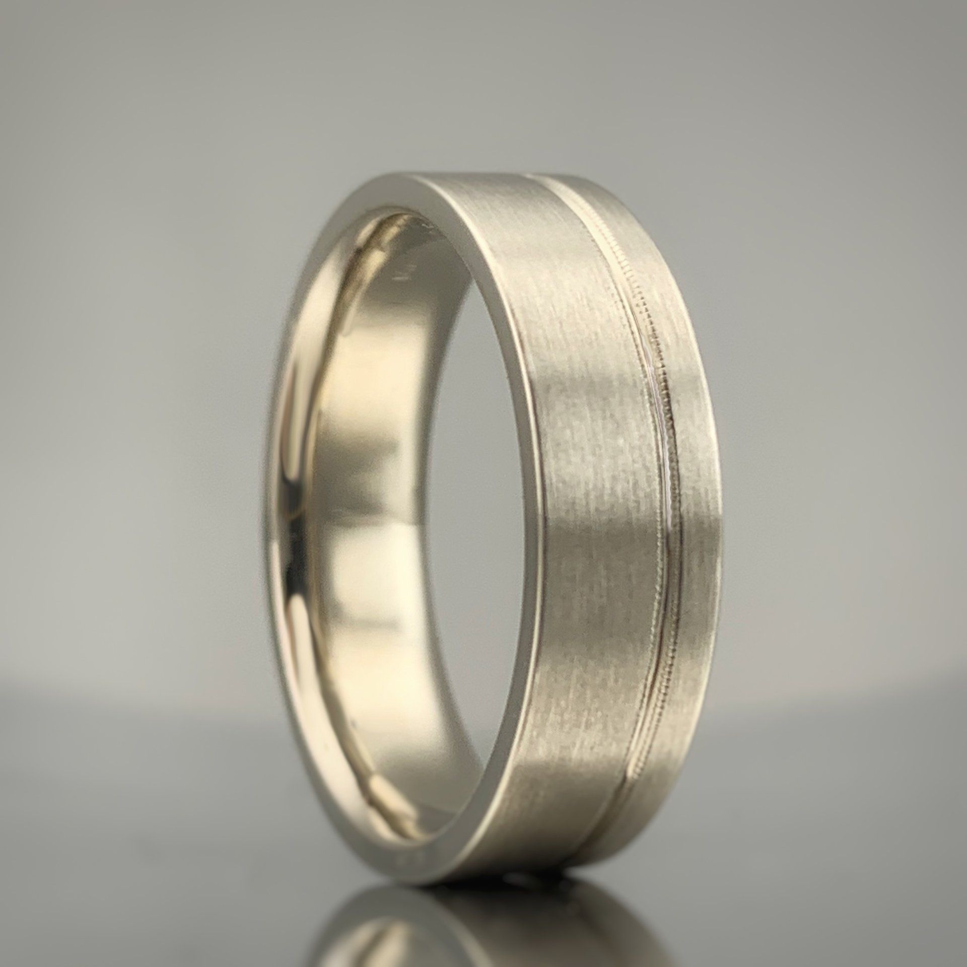 A silver ring with a brushed finish sits on a table