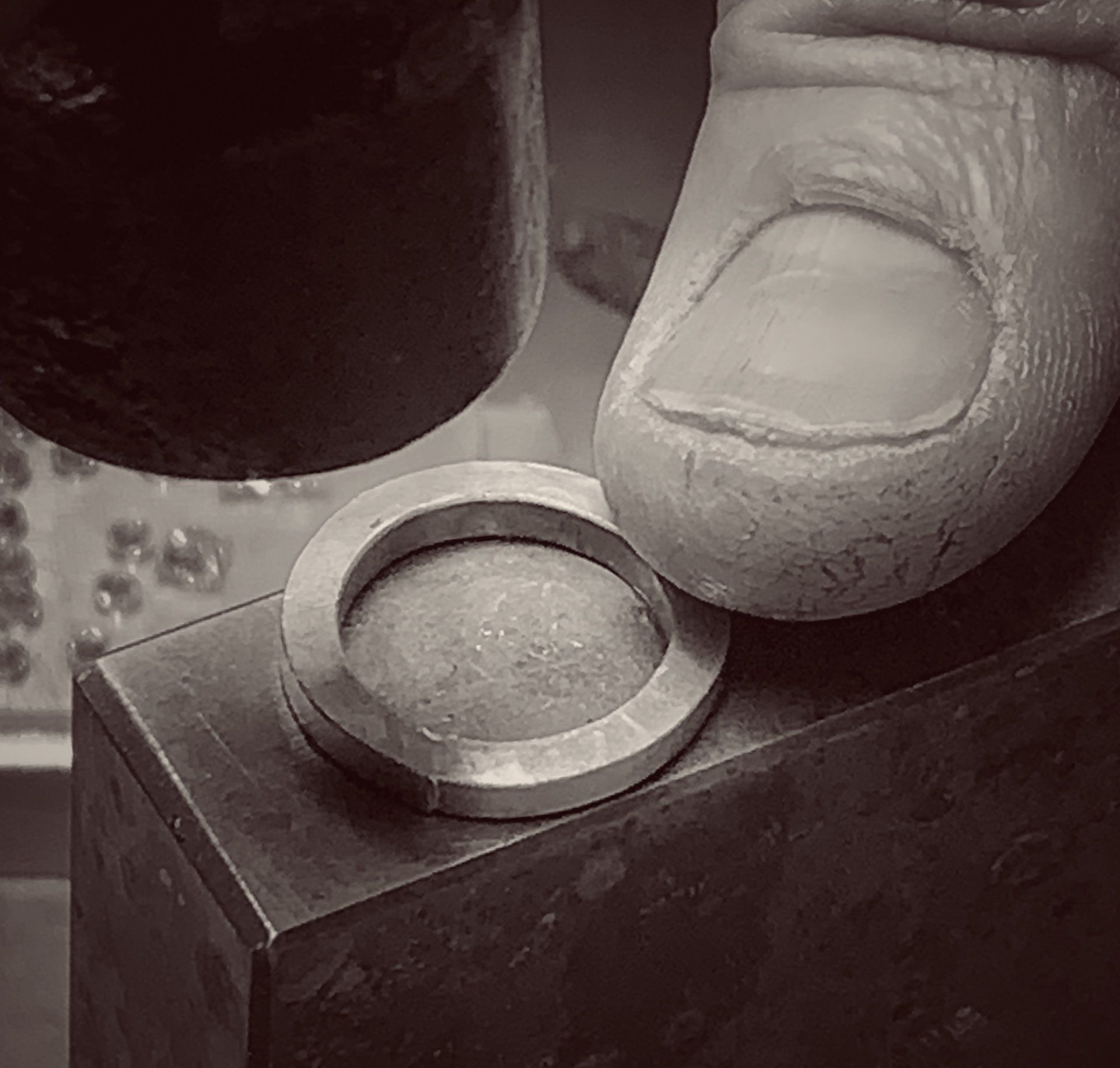 A black and white photo of a person hammering a ring