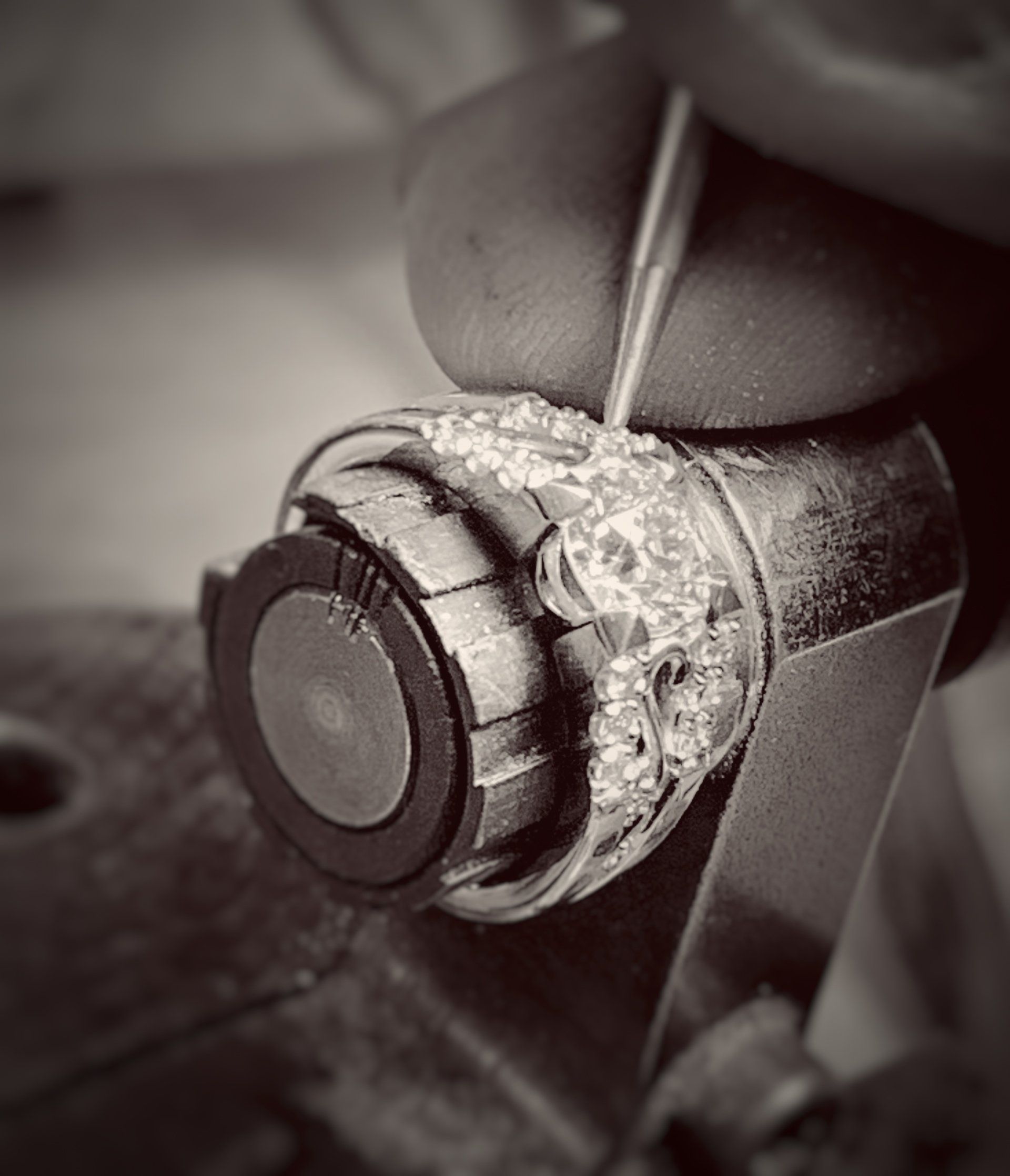 A black and white photo of a person working on a ring.