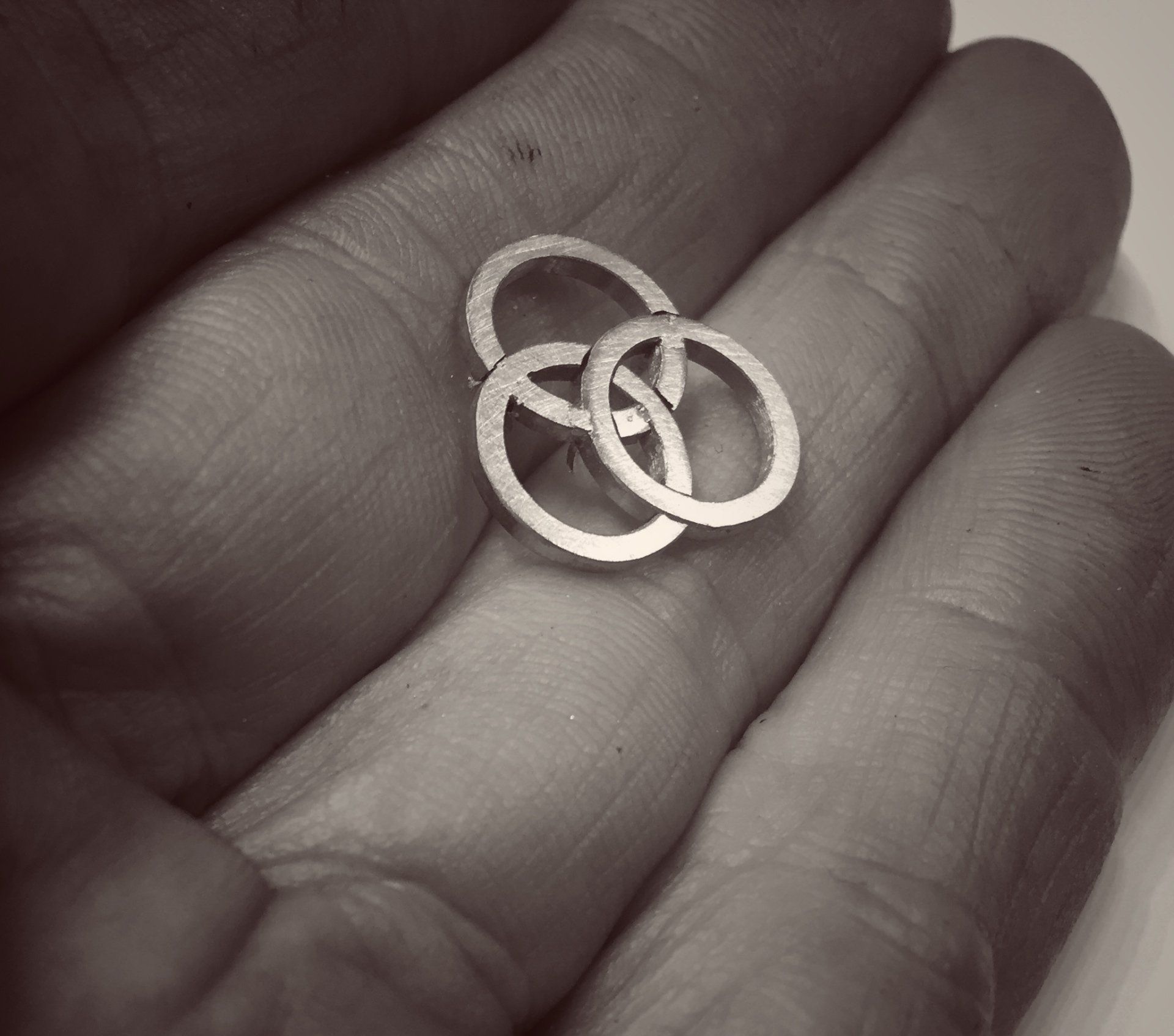 A person is holding a small silver ring in their hand