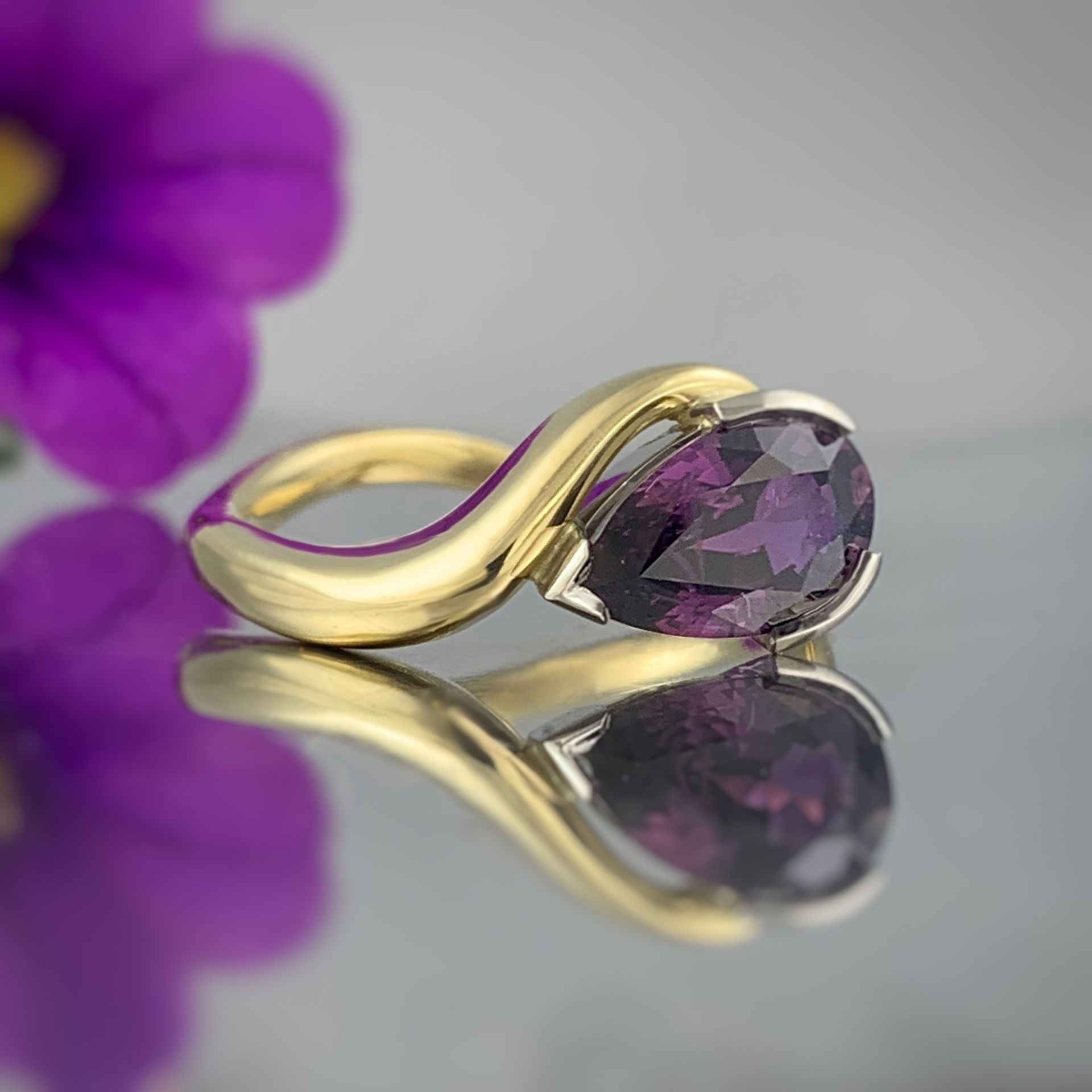 A gold ring with a purple stone in it
