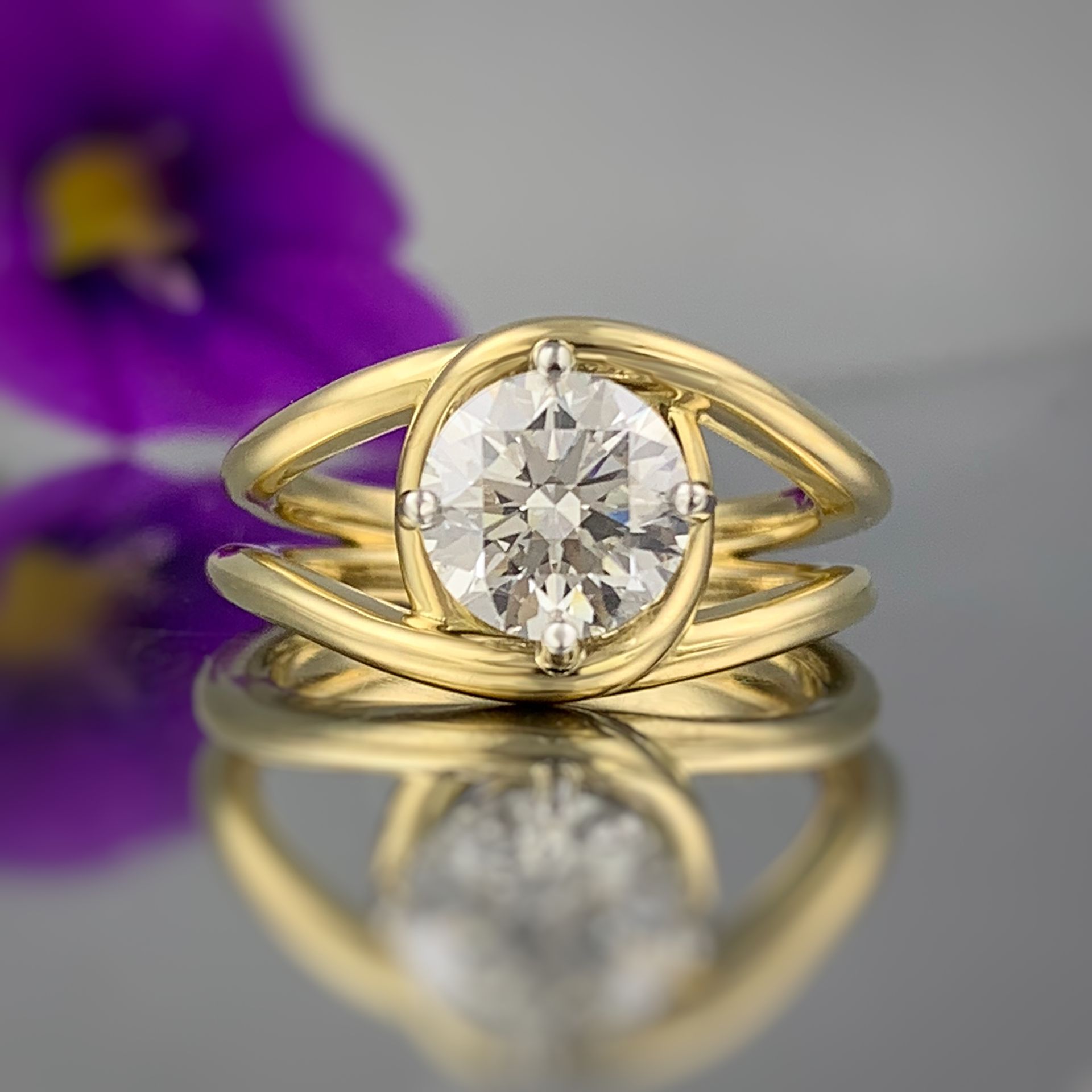 A yellow gold ring with a diamond in the center is sitting on a table.
