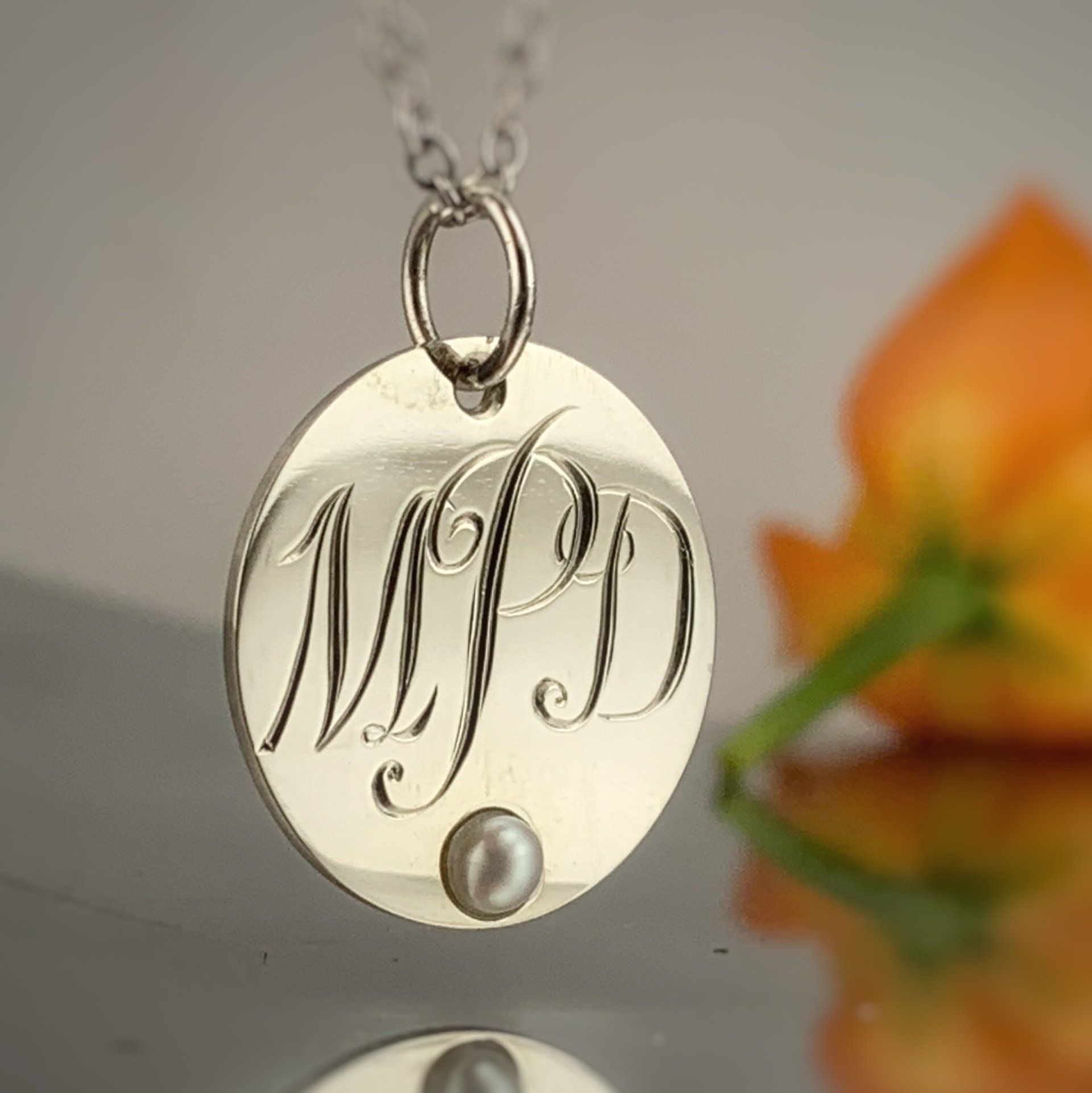 A necklace with the initials mjd and a pearl