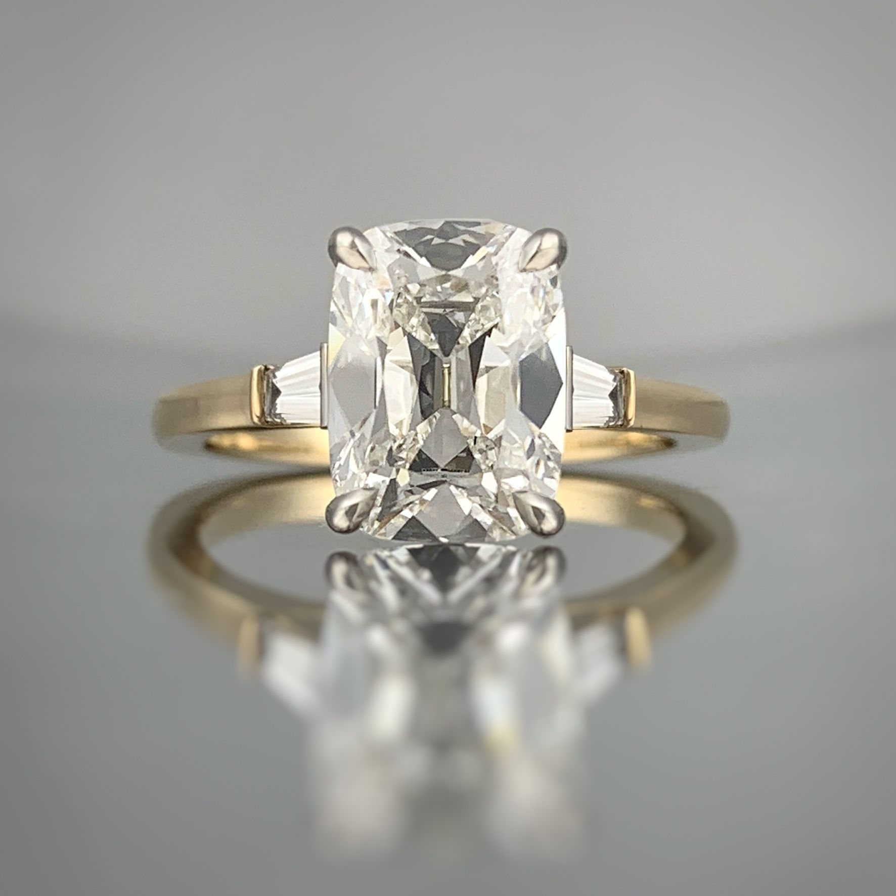 A yellow gold ring with an emerald cut diamond in the center