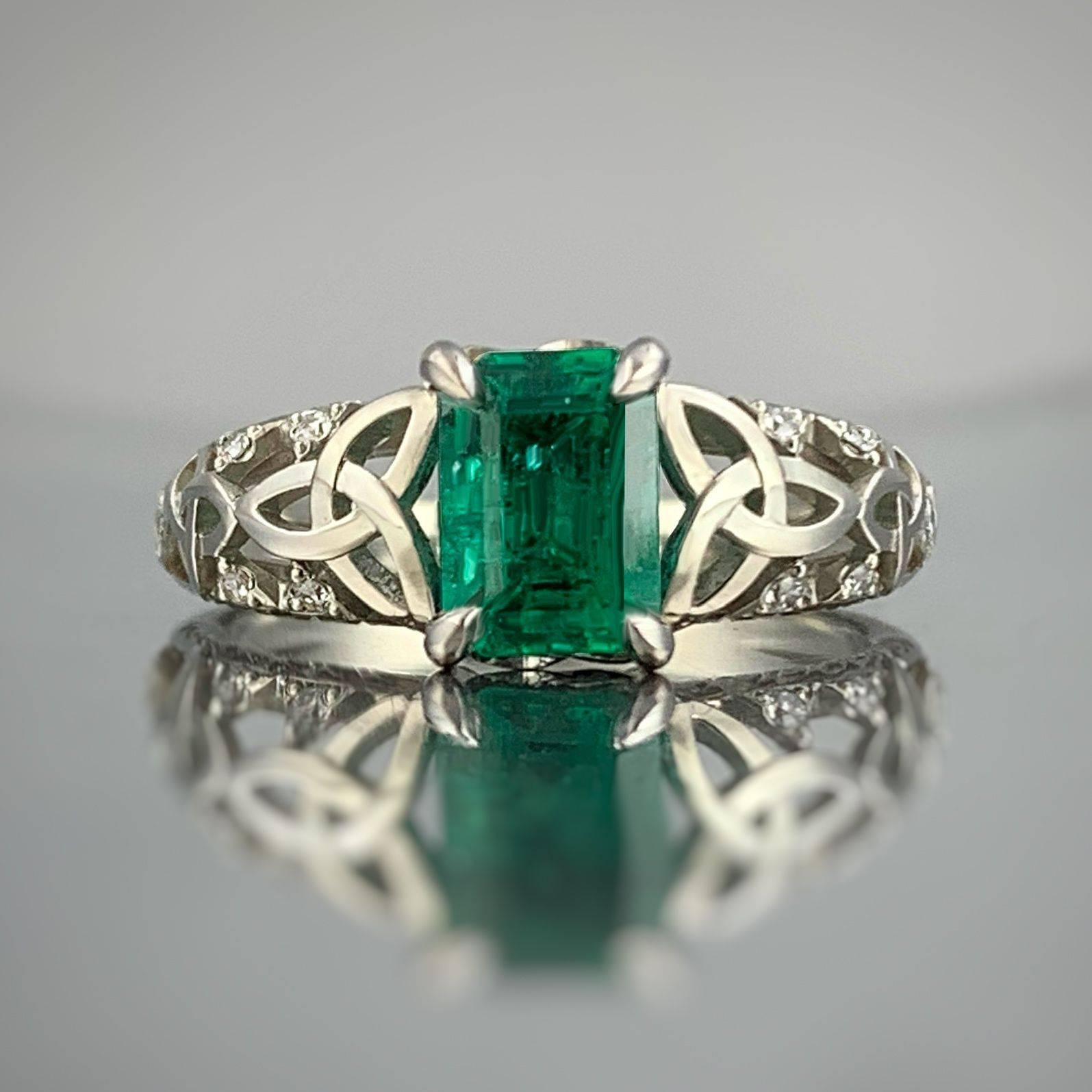 A ring with an emerald in the center is on a table.