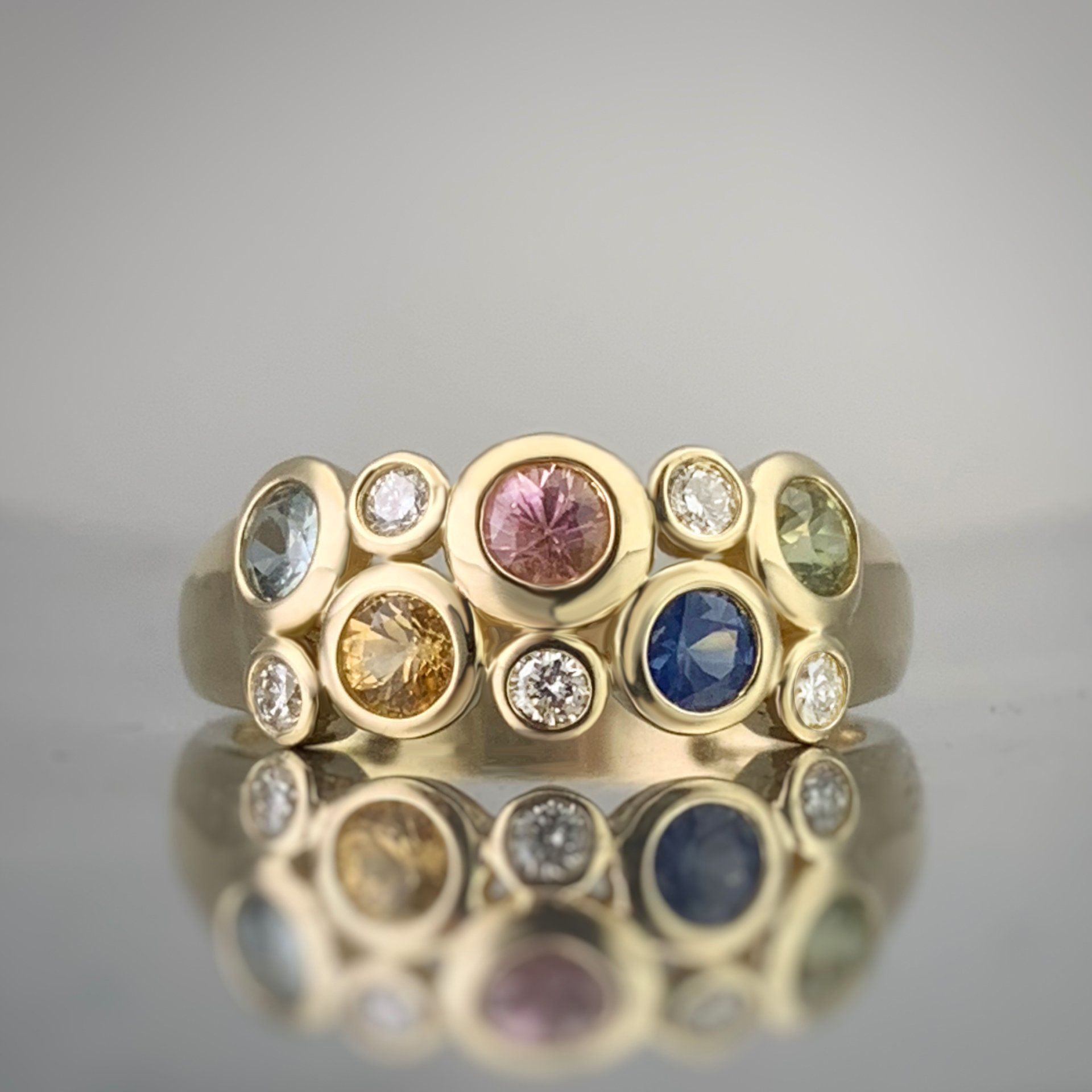 A yellow gold ring with a variety of colored stones and diamonds