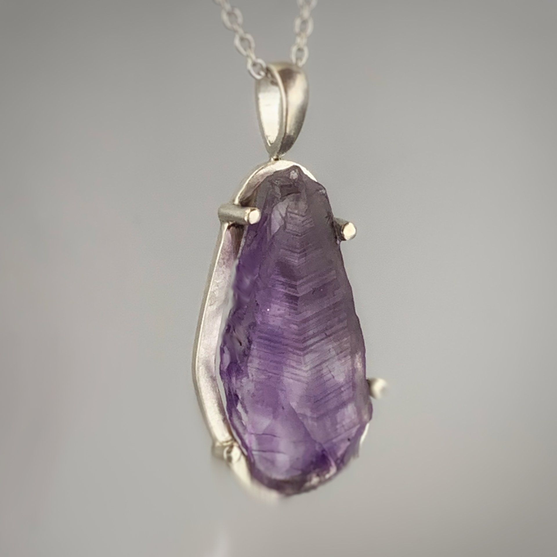 A necklace with a purple stone pendant on a chain.