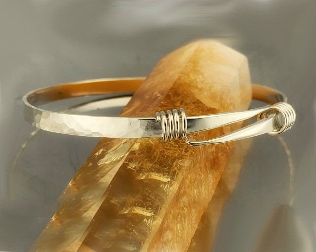 A silver bracelet is sitting on top of a piece of crystal.