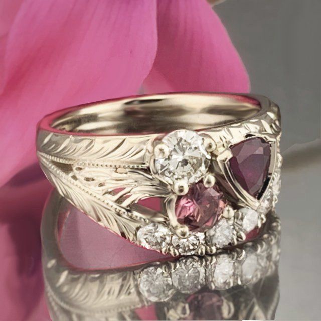 A close up of a ring with a pink flower in the background