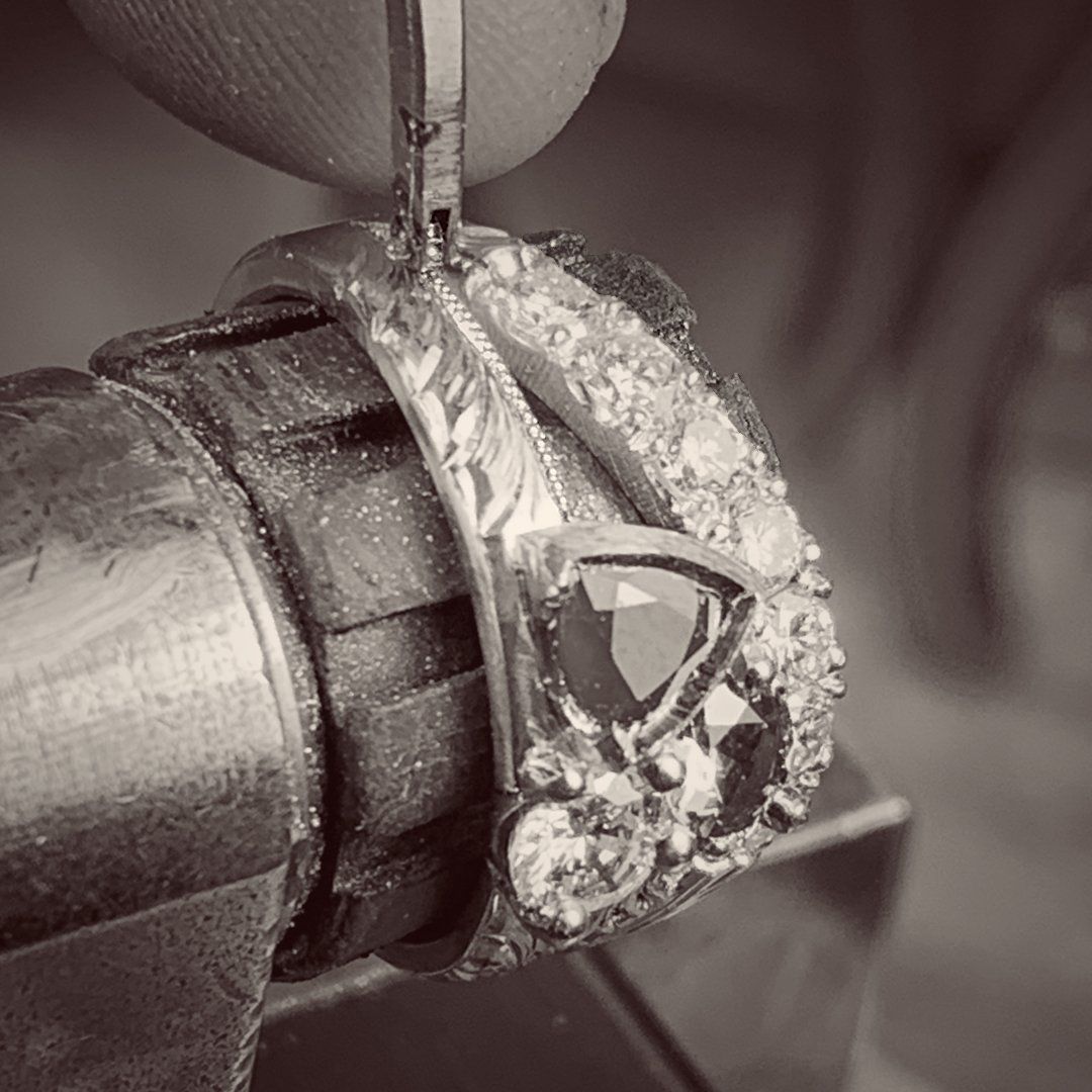 A black and white photo of a person working on a ring.
