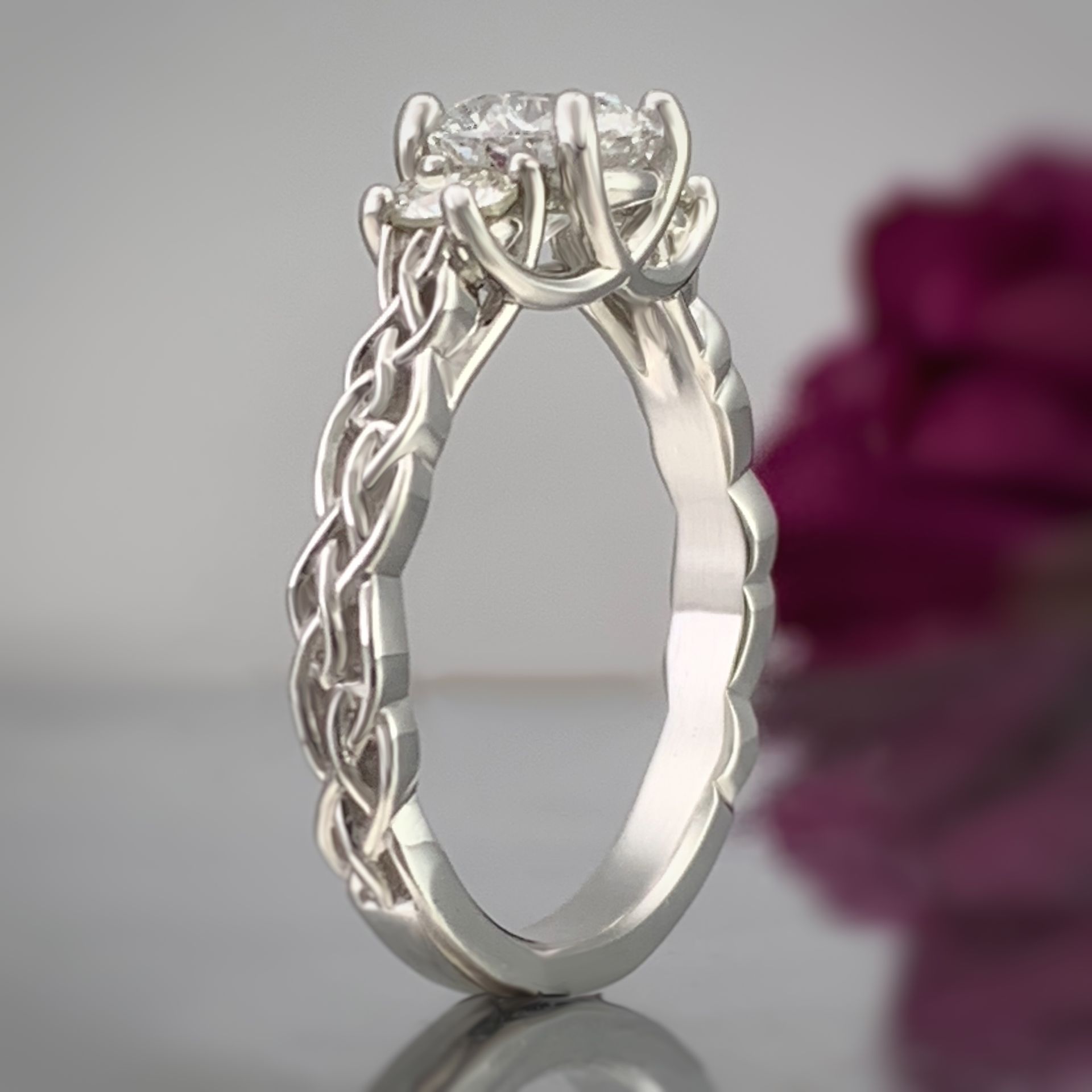 A white gold ring with a diamond in the center is sitting on a table.