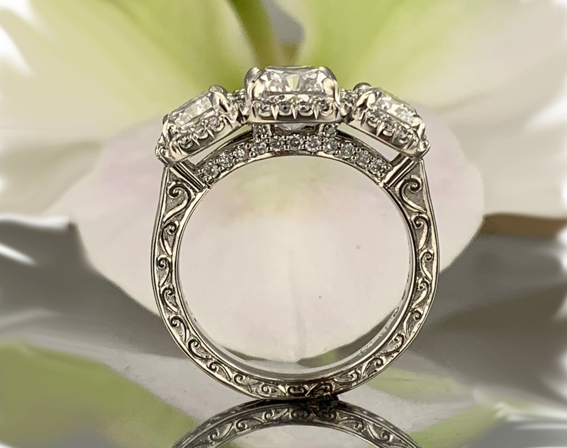 A diamond ring is sitting on top of a white flower.