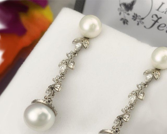 A pair of pearl and diamond earrings on a white surface