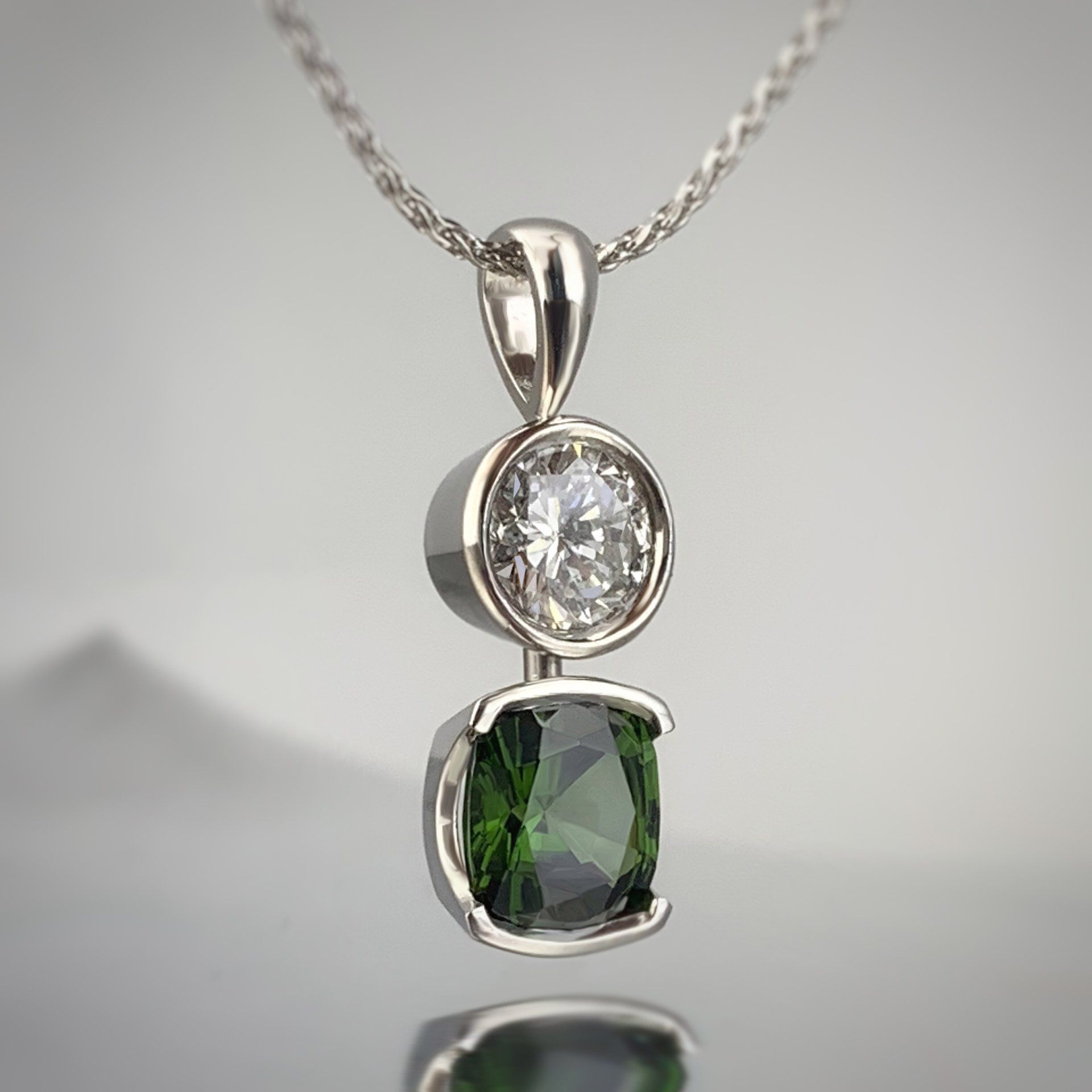 A pendant with a green stone and a diamond on a chain