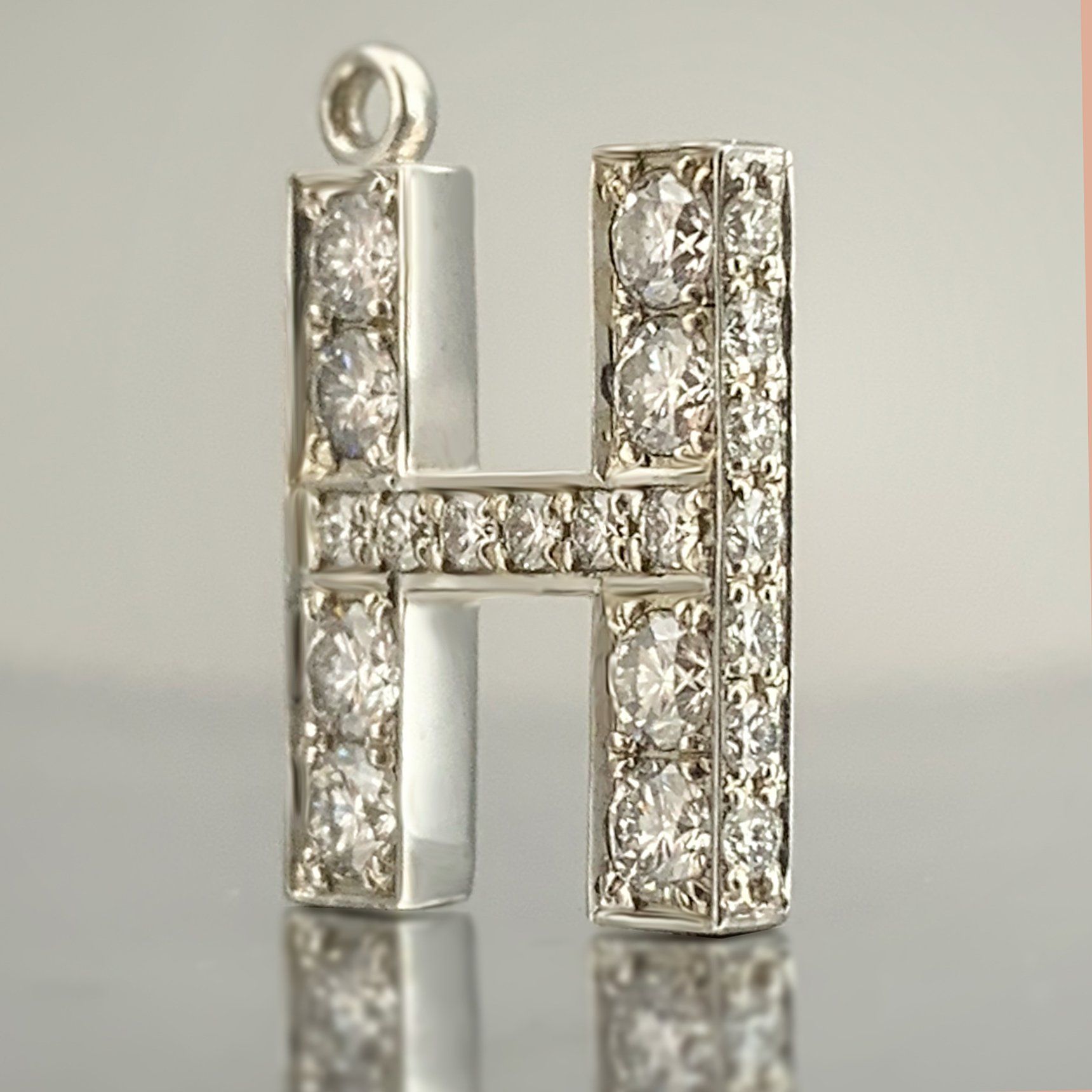 A pendant in the shape of the letter h is surrounded by diamonds