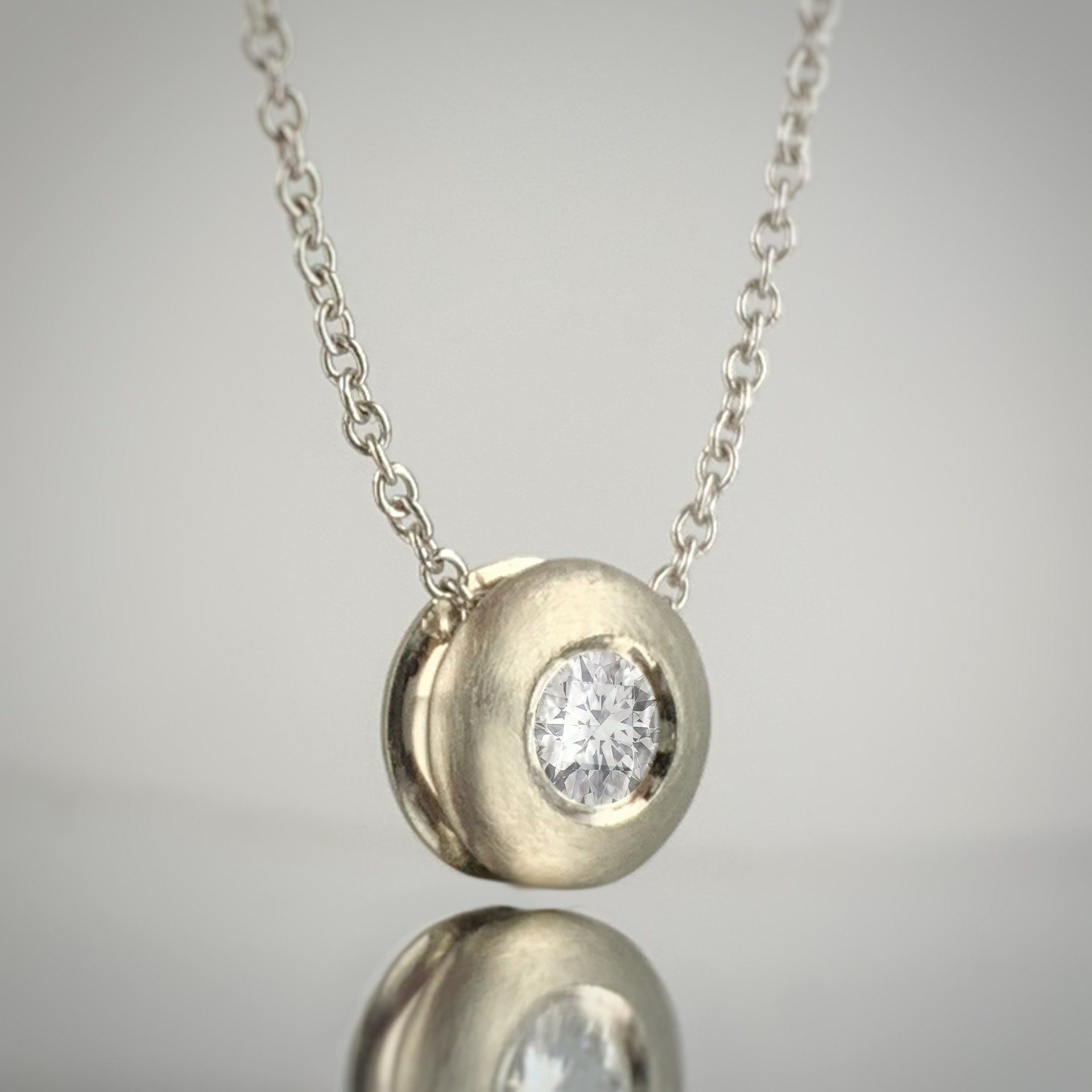 A close up of a necklace with a diamond pendant on a chain.