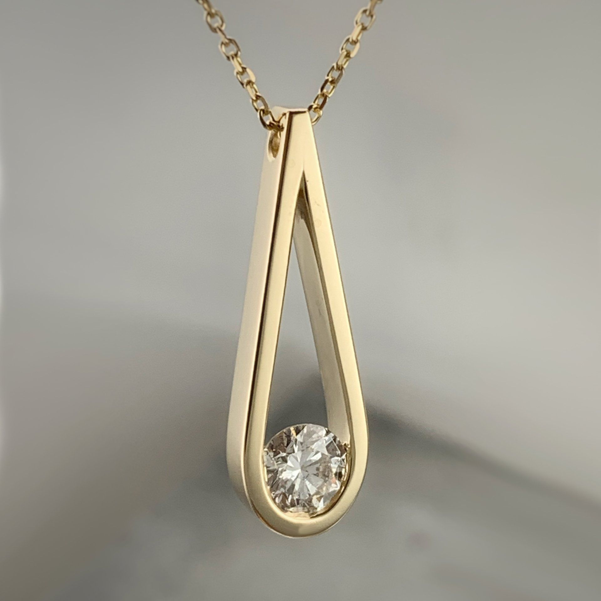 A gold necklace with a diamond in the middle