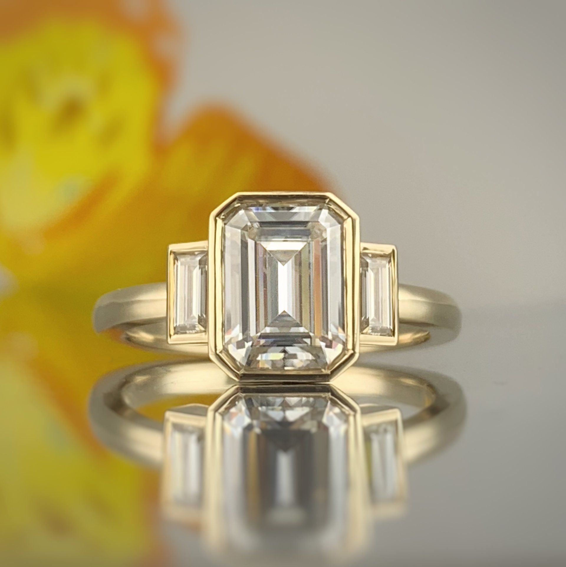 A yellow gold ring with an emerald cut diamond in the center