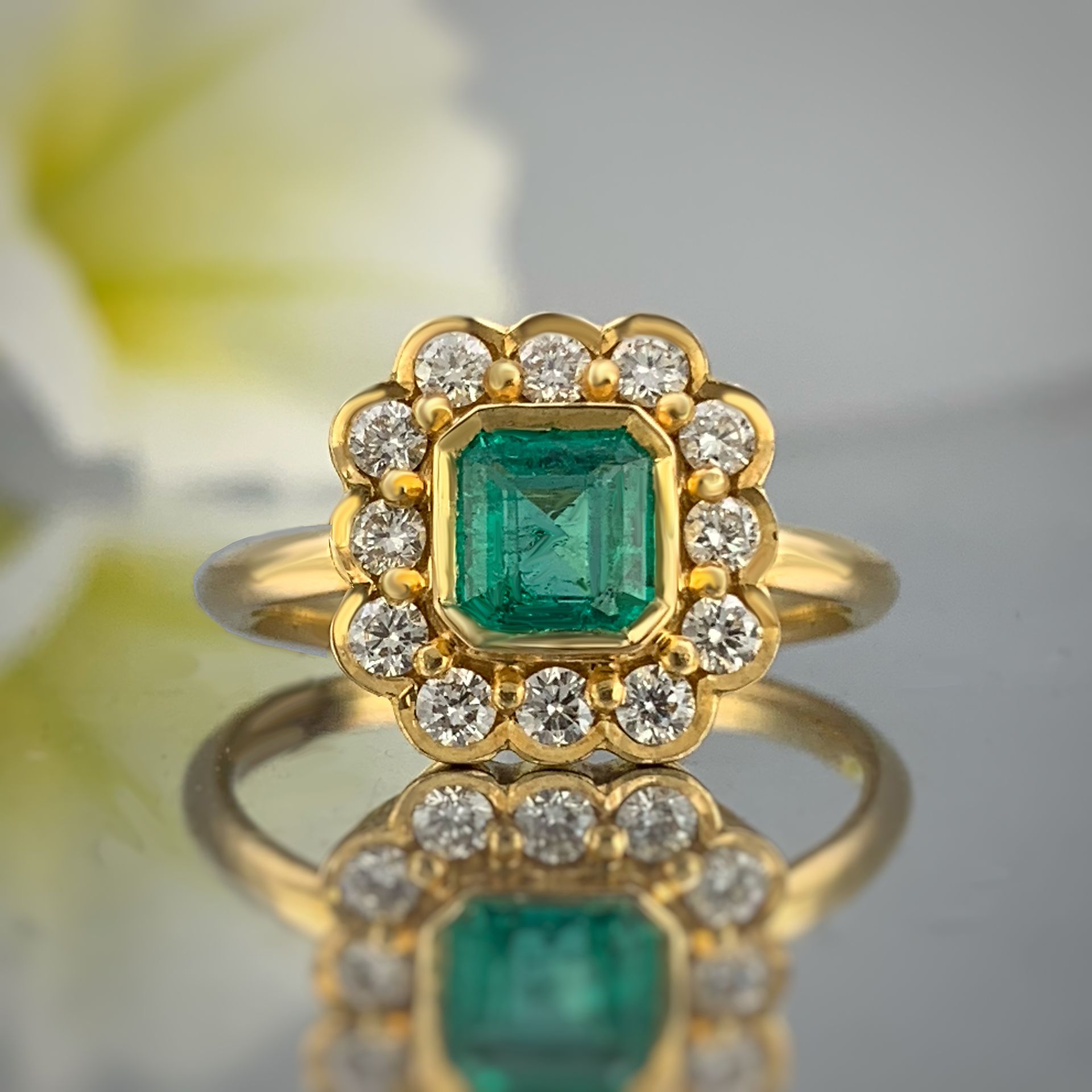 A gold ring with an emerald and diamonds is sitting on a table.