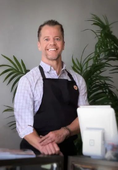 A man wearing an apron is standing in front of a computer.