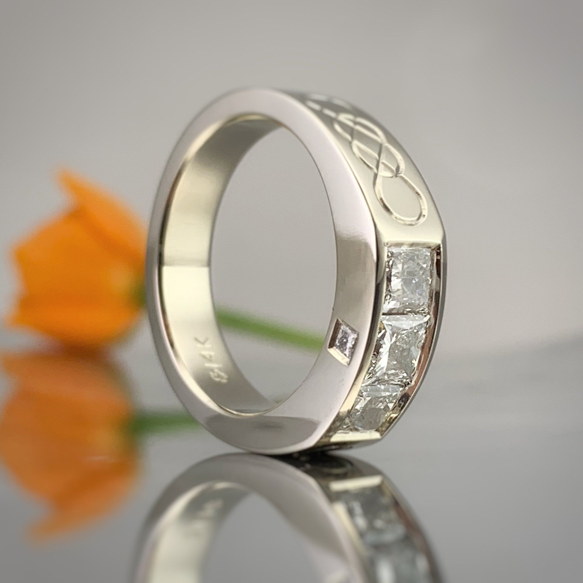 A silver ring with a flower in the background