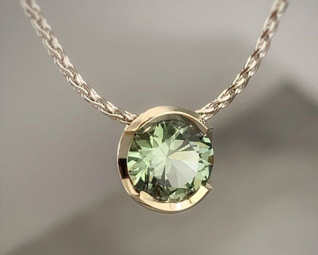 A necklace with a green stone pendant on a chain.