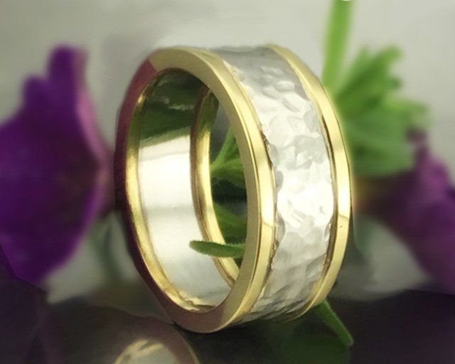 A gold and silver ring with purple flowers in the background