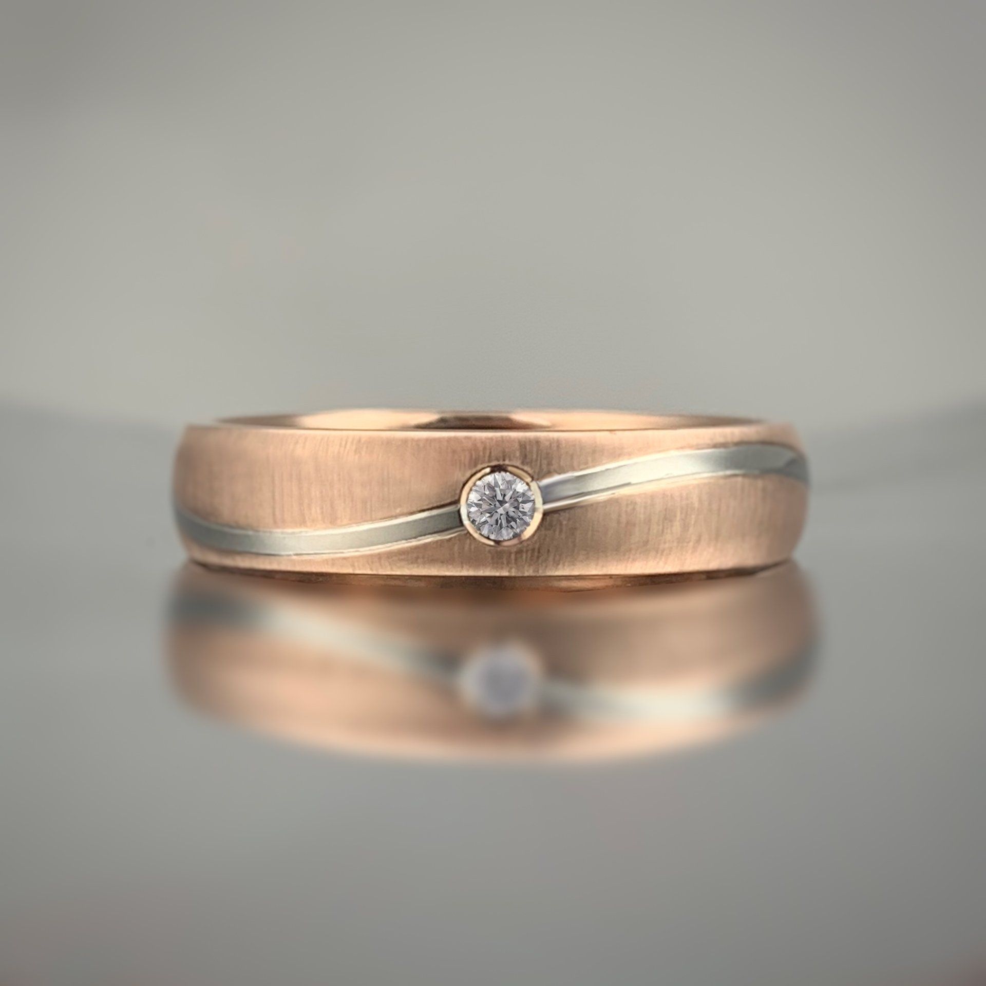 A gold ring with a diamond in the center is on a table.
