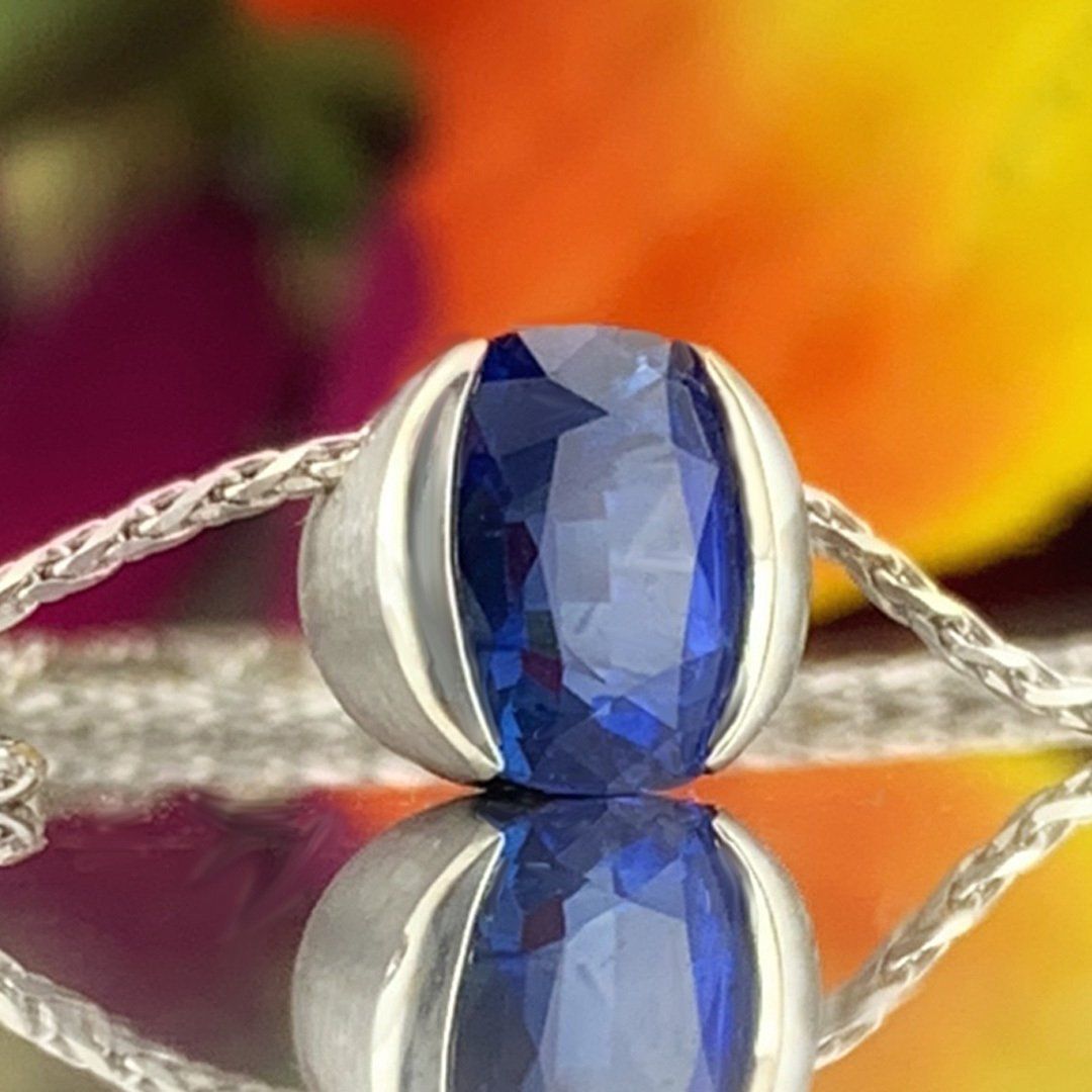 A close up of a sapphire pendant on a chain on a table.