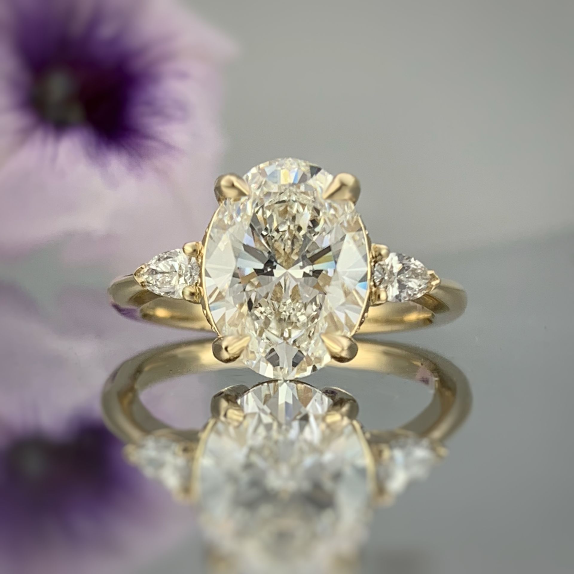 A close up of a diamond ring with a flower in the background