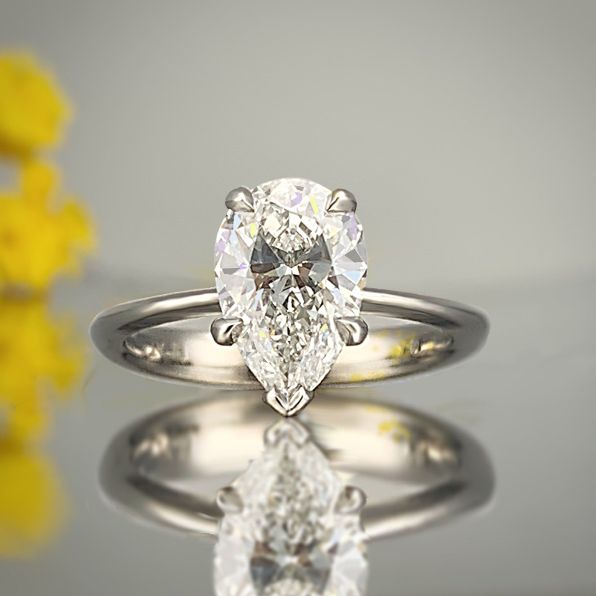 A pear shaped diamond ring is sitting on a table.