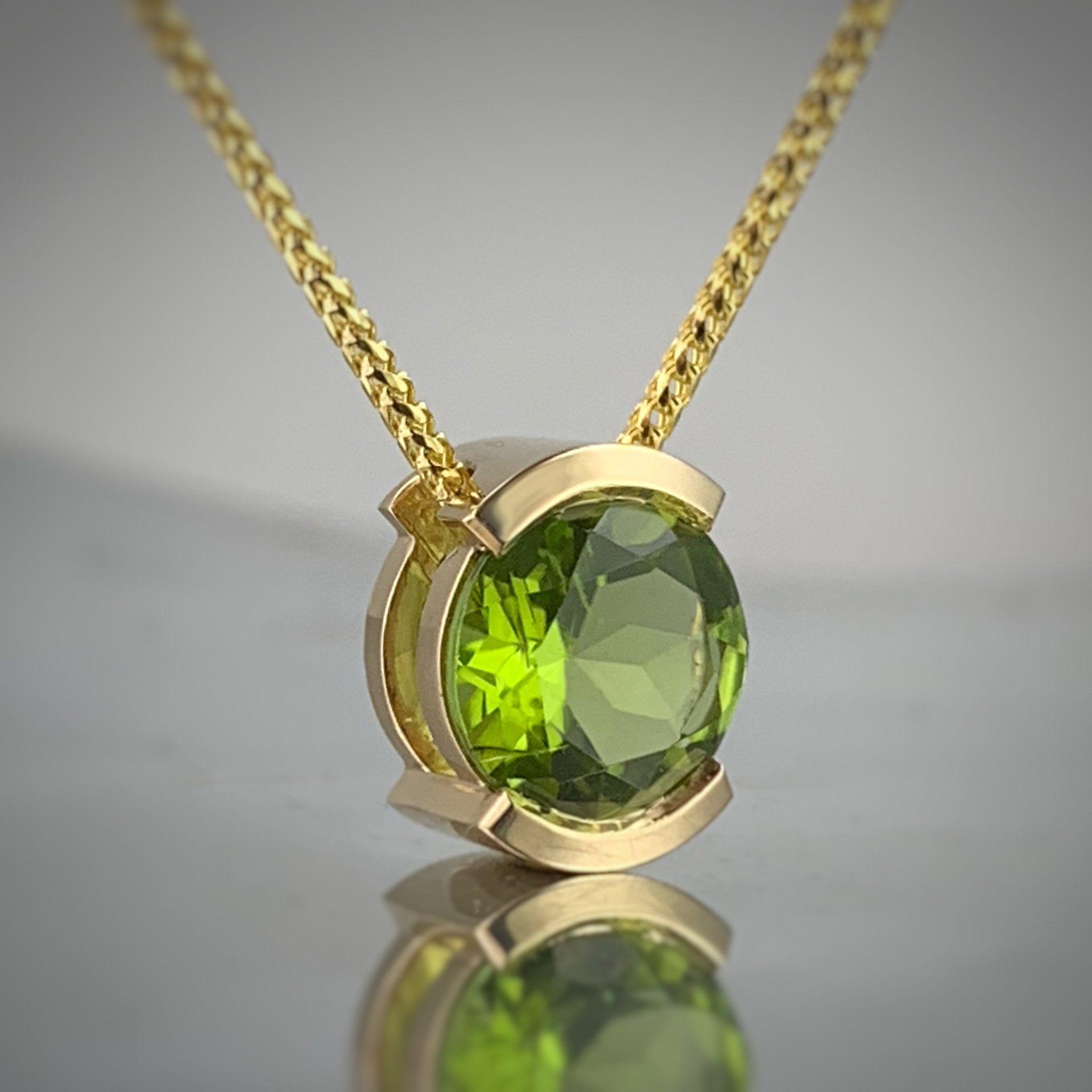 A yellow gold necklace with a green stone pendant