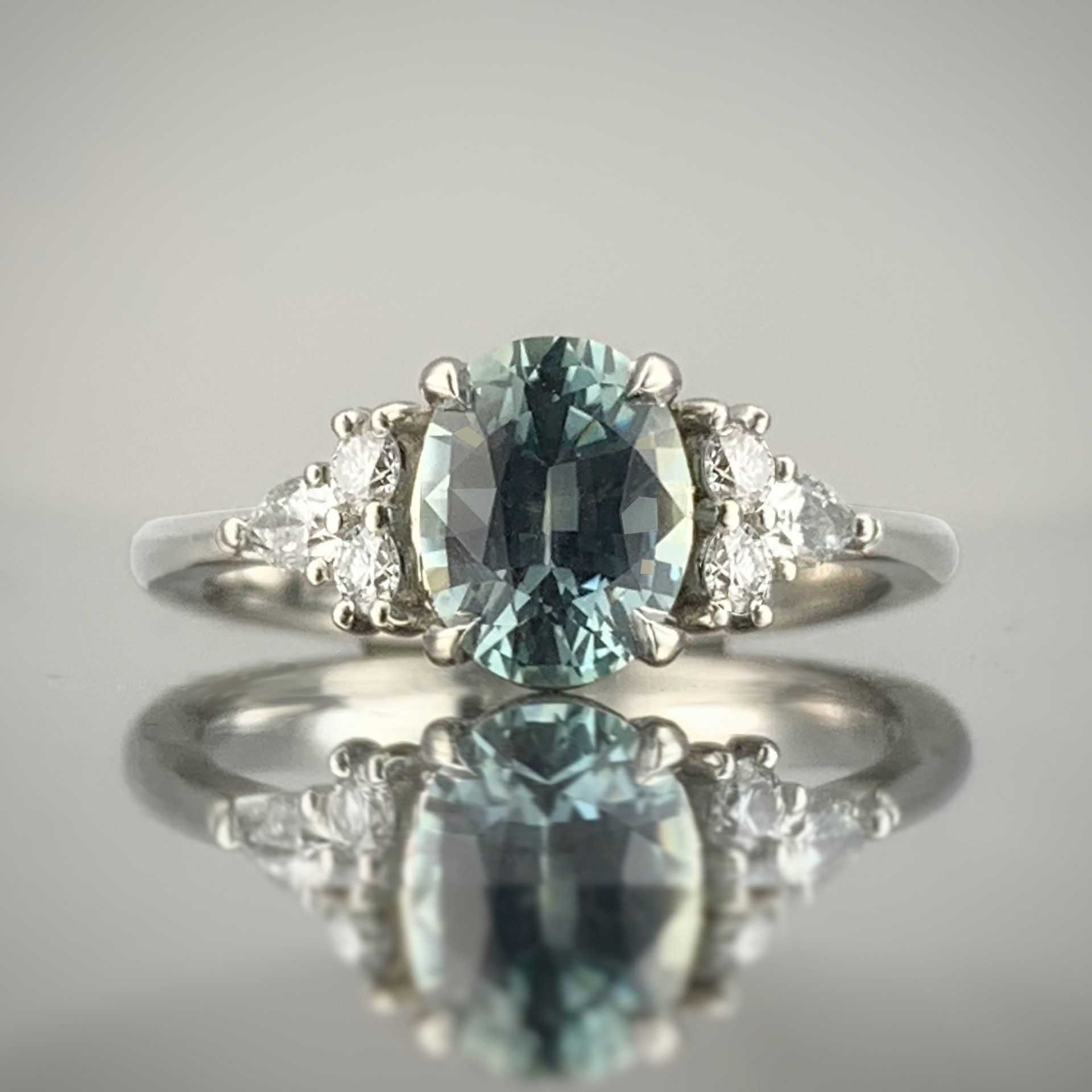 A close up of a ring with a blue stone and diamonds on a table.