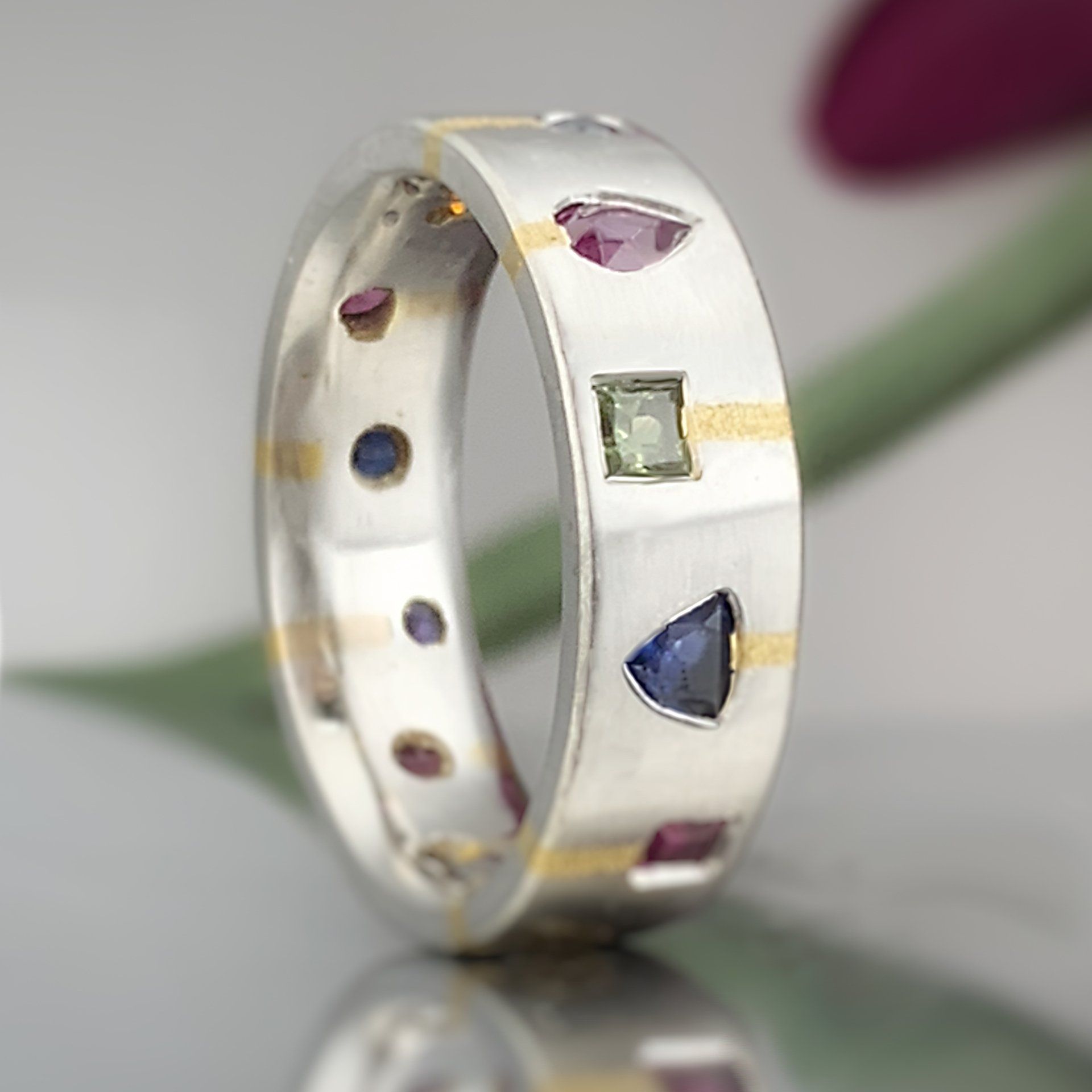 A silver ring with various colored stones on it