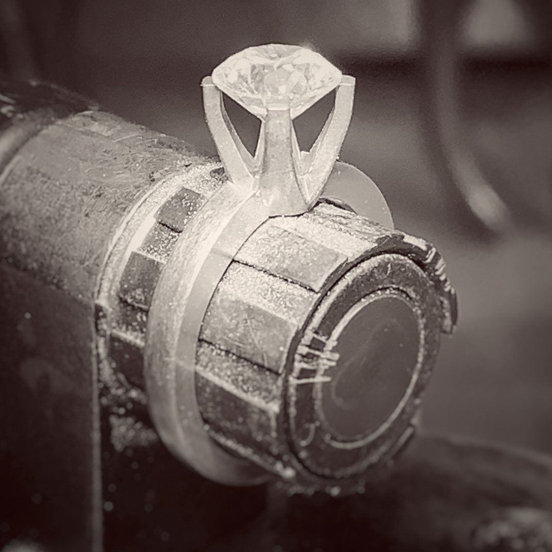 A diamond ring is being made on a machine in a black and white photo.